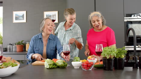 caucasian woman, asian woman, and senior biracial woman enjoy a home cooking session preparing a mea