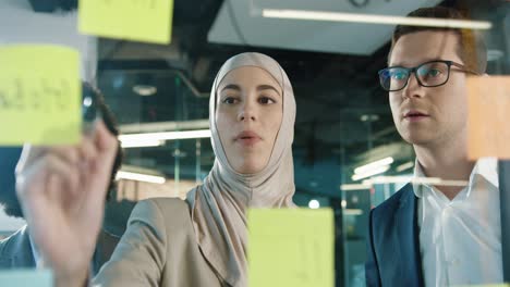 close up view of multiethnic business people group working in a modern office while writing on glass in a cabinet with sticky notes 1