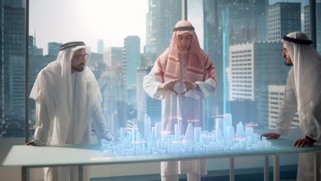un grupo de desarrolladores de negocios inmobiliarios musulmanes con ropa tradicional discuten oportunidades de inversión basadas en un modelo de ciudad 3d de realidad aumentada holográfica en su oficina moderna en un rascacielos.