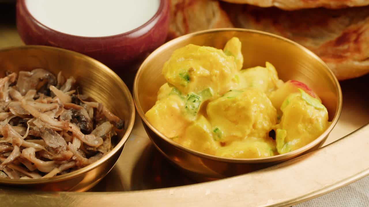 Assorted indian sri-lanka food set on wooden background. Dishes and appetisers of indeed cuisine, rice, lentils, paneer, samosa, spices, masala. Bowls and plates with indian food top view chicken. High quality 4k footage