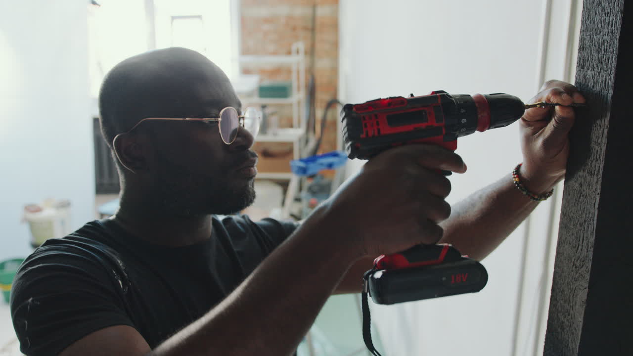 African American Man Drilling Screw into Door Frame at Home