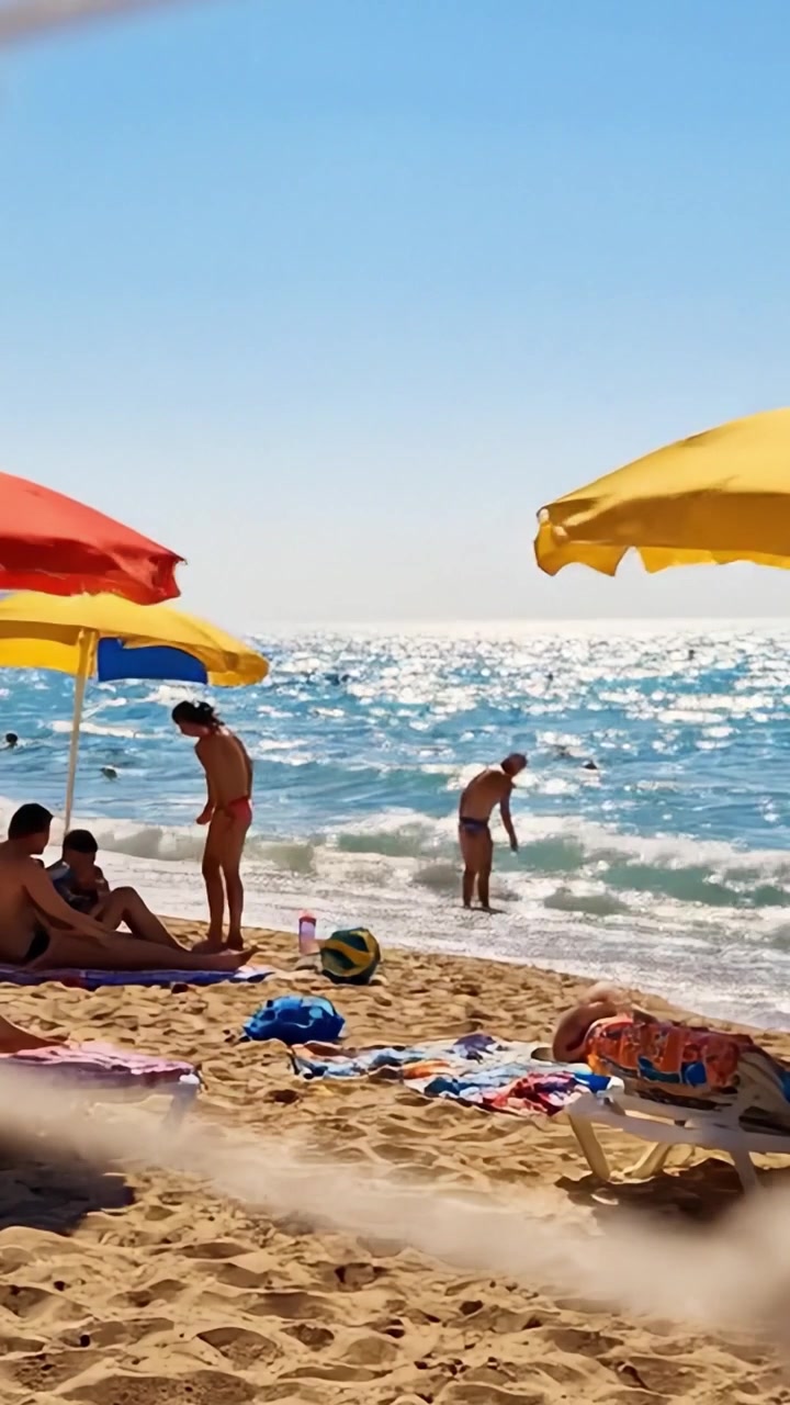 Una Giornata Rilassante in Spiaggia - Ombrelloni Vivaci, Bagnanti e Onde Creano una Perfetta Atmosfera Estiva sul Litorale