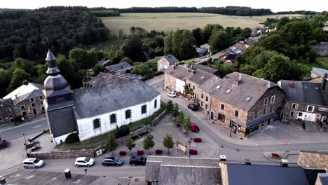 aproximación aérea hacia la iglesia en un pequeño pueblo idílico en bélgica ardennes