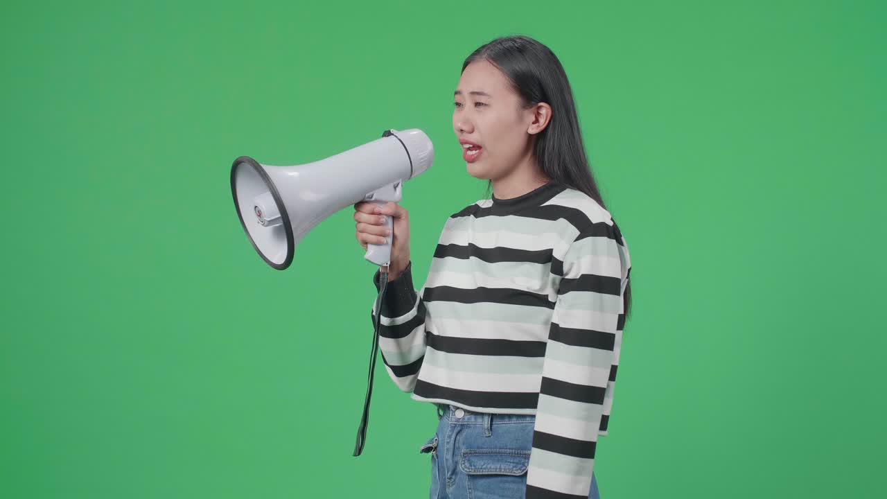 Side View Of Asian Woman Speaking On Megaphone In The Green Screen Studio