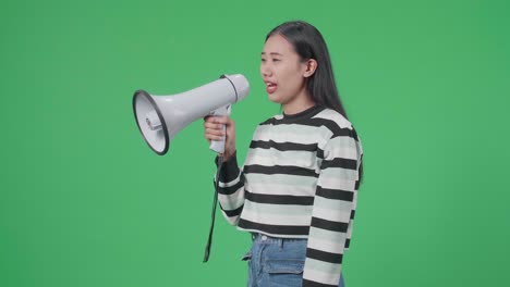 side view of asian woman speaking on megaphone in the green screen studio