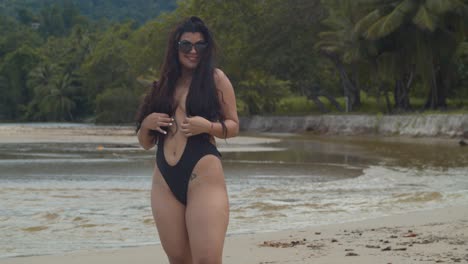 sexy latina girl in a swimsuit dancing and enjoying herself at the beach with a river flowing in the background