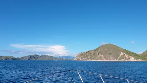 overlooking the bow front of tour boat moving fast over ocean with view of tropical islands in komodo national reserve in indonesia