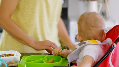 madre preparando el desayuno para su bebé en la cocina 4k