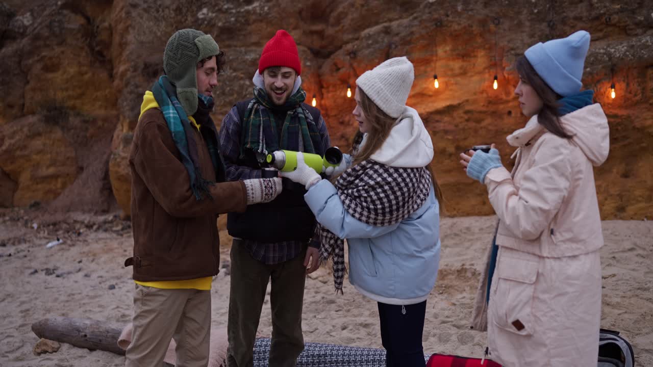 Friends enjoying hot drinks on a winter beach