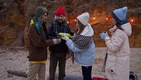 friends enjoying hot drinks on a winter beach