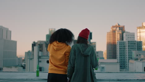 rear view young women friends taking selfie photos on rooftop at sunset enjoying hanging out together drinking alcohol sharing friendship looking at urban city skyline