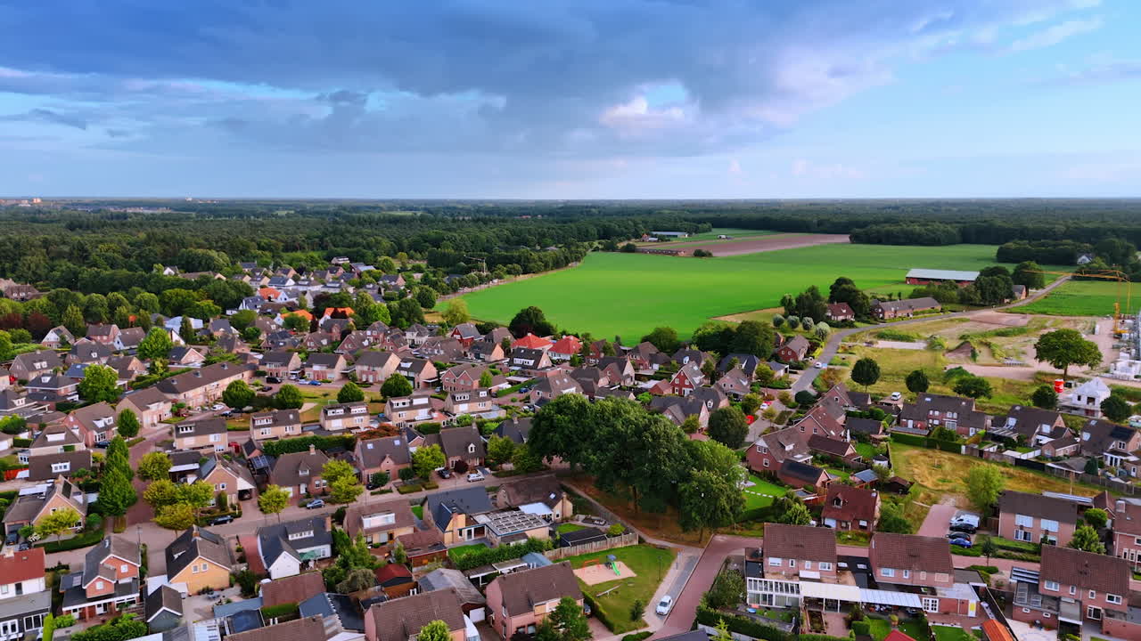 Multiple houses in the densely built residential area of a picturesque village. Beautiful fields and lush forests at backdrop. Overloon, Netherlands