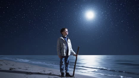 young boy gazing at a bright moon on a starry night beach