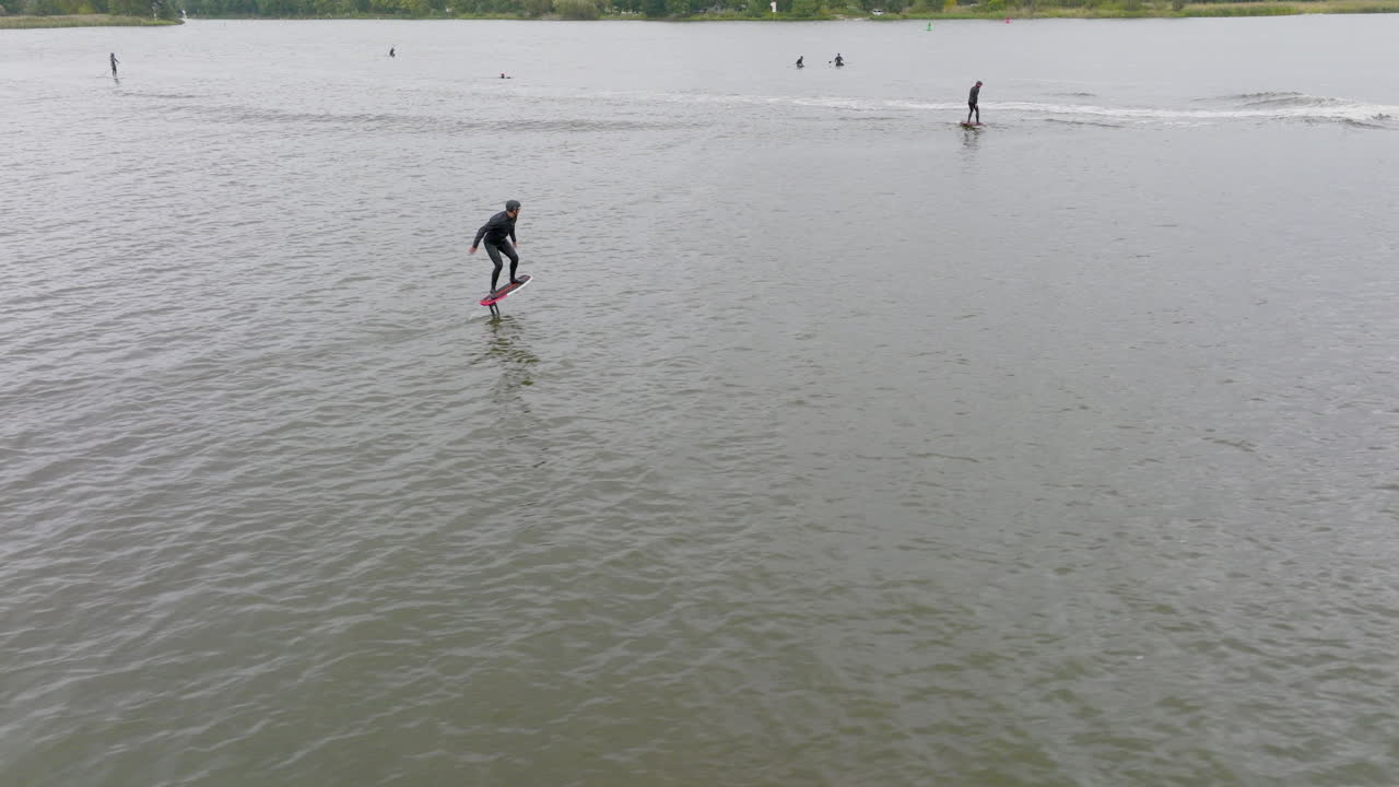 los hidrofoilers están bombeando a las embarcaciones para surfear las olas detrás de él con el sup foiler en el fondo