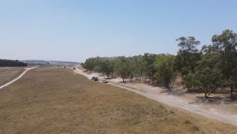 Israel-Army-squad-soldiers-on-vehicles-driving-through-training-ground-country-road,-Aerial-Tracking-shot