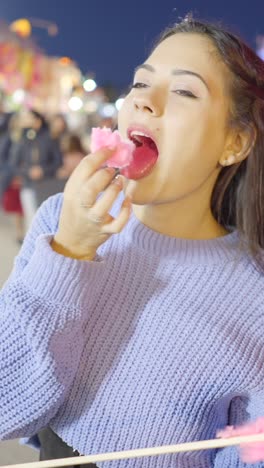 young woman enjoying cotton candy at a night fair