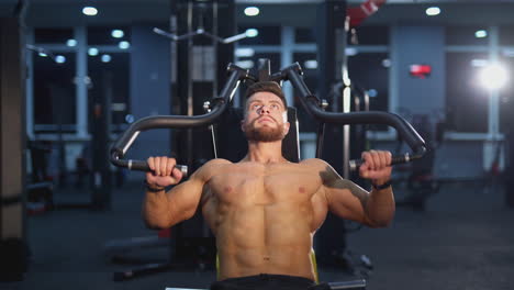 training muscles. sportsman pumping his trained body on a simulator. strong trainer doing workout. bodybuilder doing exercise on the modern simulator in the gym.