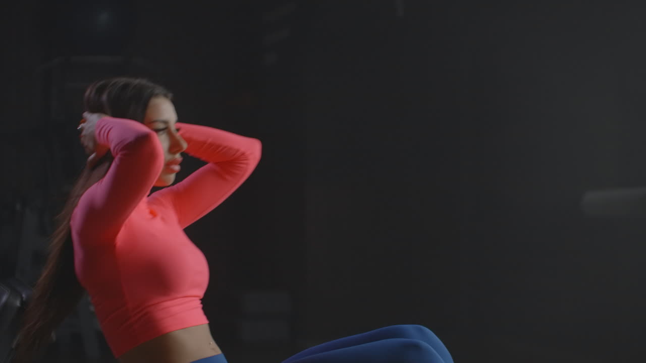 молодая девушка занимается упражнениями на брюшной полости в тренажерном зале. она контролирует свое дыхание и технику. это отличная утренняя тренировка в фитнес-центре.