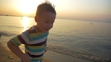 child making angry face on the beach at sunset