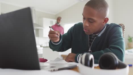 video of focused african american boy with laptop having online lessons at home