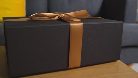 close up of gift wrapped present with bow on table in lounge at home 4