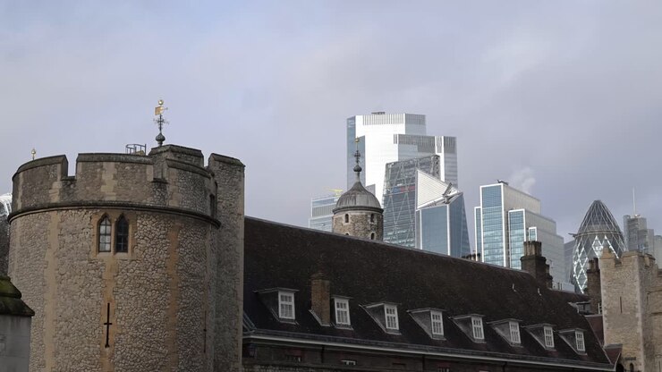 Storica Torre di Londra che si erge di fronte al moderno skyline della City di Londra, contrapponendo antiche mura in pietra all'architettura contemporanea in vetro.