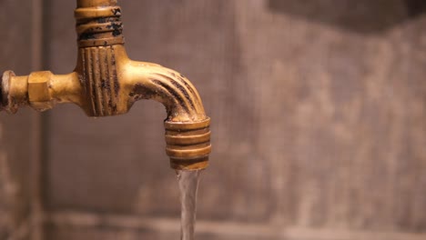 close up of a vintage brass faucet with water flowing
