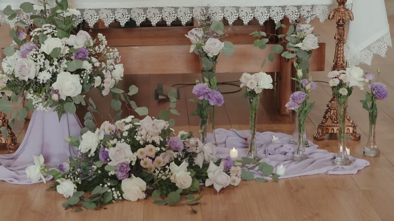 Bunga dan lilin ditata di lantai dekat altar kayu