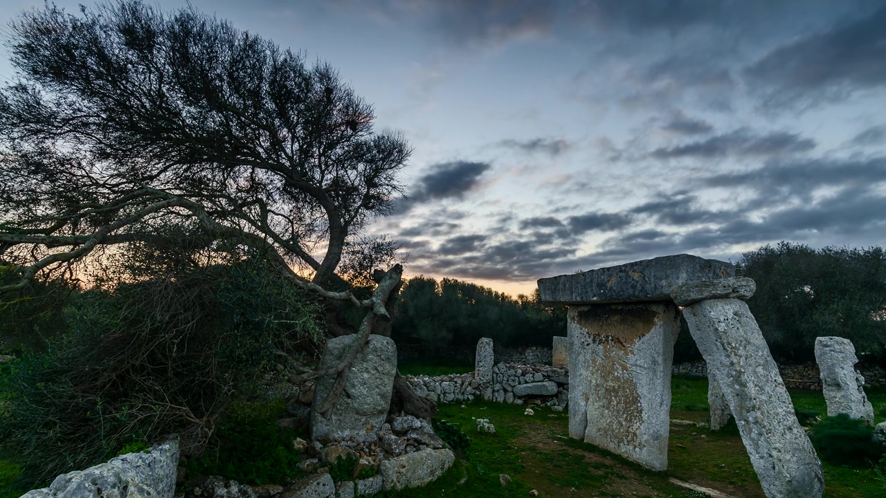 Timelapse delle antiche rovine di Talati de Dalt a Minorca, Spagna, con luce mutevole e nuvole che passano sul paesaggio mediterraneo con alberi spogli.