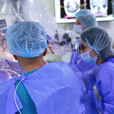 team of doctors working in surgery room. neurosurgeons looks attentively at microscope.