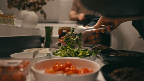 Tomada-A-Través-De-Un-Mostrador,-Capturando-Comida-De-Autoservicio-Para-Personas-Y-Familias-En-Una-Vibrante-Barra-De-Ensaladas.