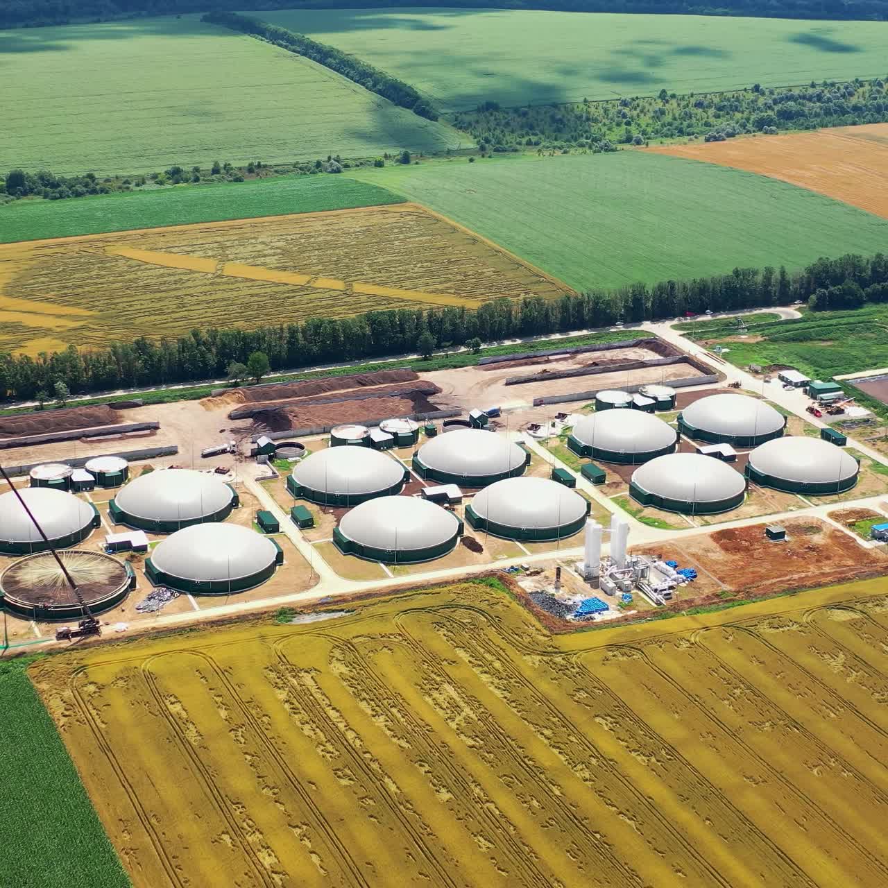 Organic farm on field. Biogas complex on agricultural lands background. View from above of storage tanks. Energy production plant. Aerial view