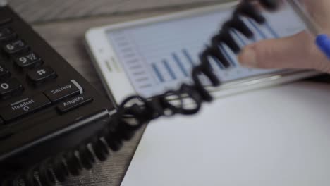 busy person in phone conversation while looking at graph on a tablet