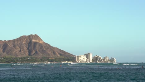 Surfers-enjoy-a-nice-sunny-evening-with-Diamond-Head-on-Oahu,-Hawaii-in-the-background