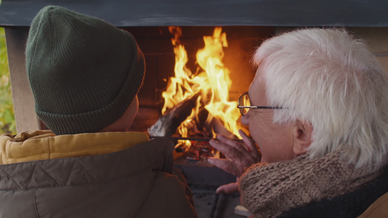 Child and Granddaddy Warming Hands by Fire and Chatting