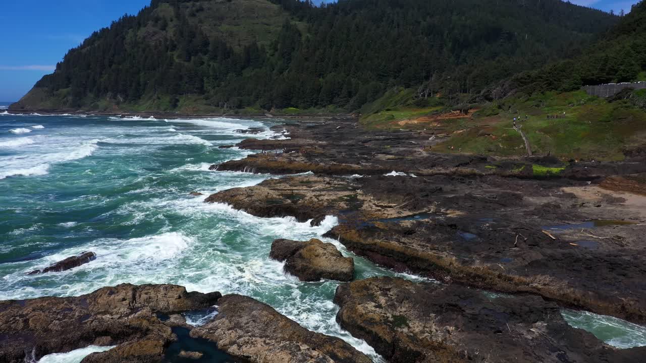 Aerial view flying over rocky sea shore with ocean waves off the coast of California.