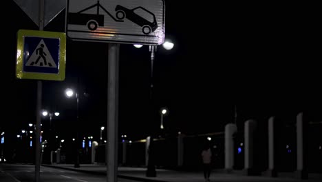 night scene on a city street with signs and people