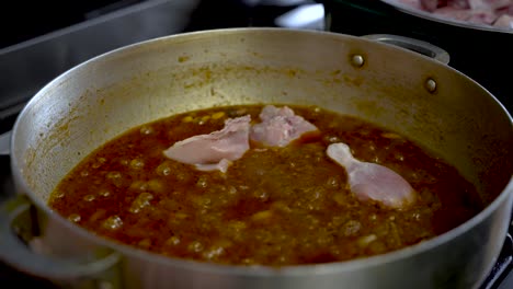 se colocan trozos de pollo crudo y se cocinan en salsa de curry a fuego lento en una olla