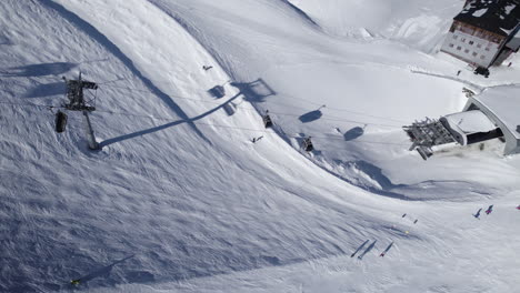 Toma-Aérea-De-Remonte-Y-Gente-De-Esquí-En-La-Estación-De-Esquí-Durante-El-Día-Soleado-En-La-Temporada-De-Invierno---Austria,-Europa