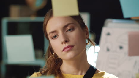 Closeup-focused-hipster-girl-reading-stickers-on-glass-board-in-hipster-office