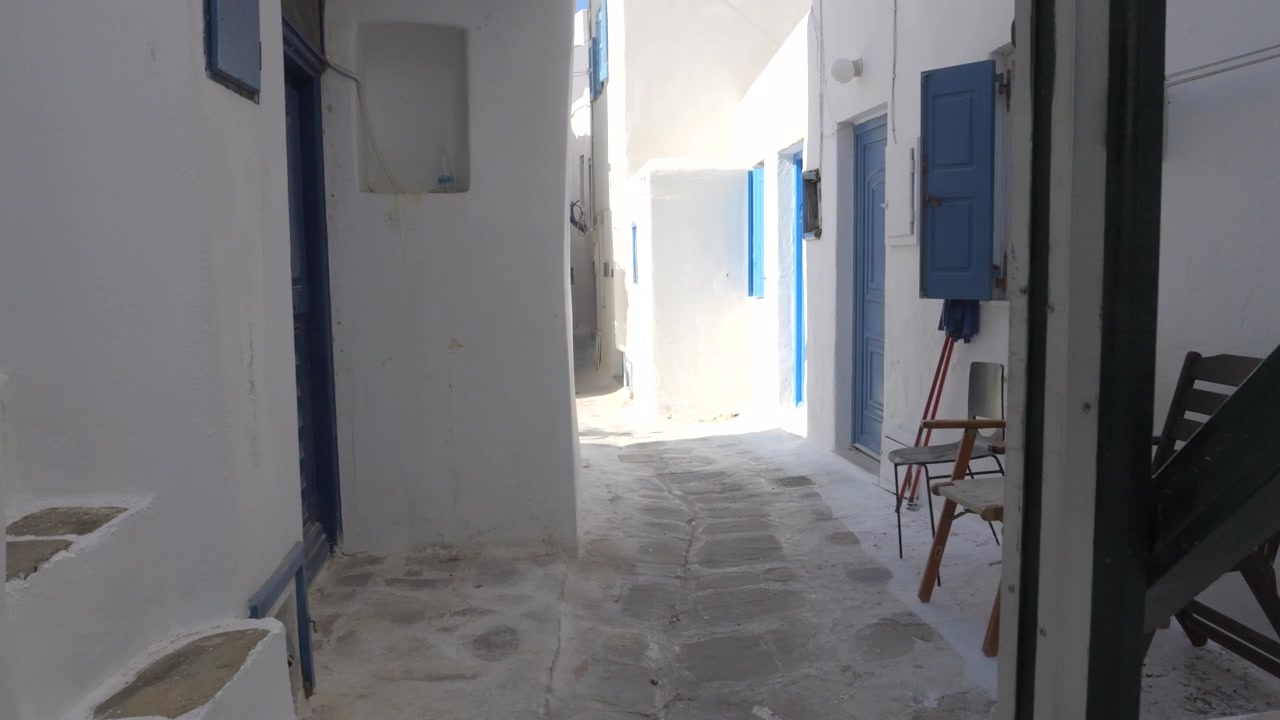 Esplorando un pittoresco vicolo di Mykonos, mostrando iconici edifici bianchi, porte blu e architettura tradizionale delle isole greche