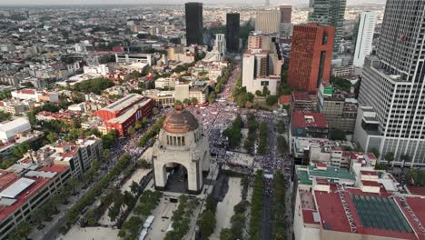 cinematic drone shot over a crowd gathered at the monument of revolution in the city of mixquic in mexico