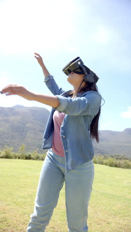 vertical video: using vr headset, woman enjoying virtual reality experience outdoors with friends