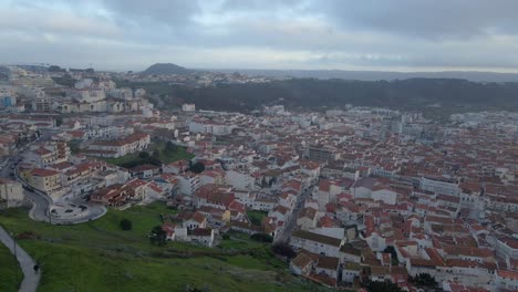 areal drone footage of the town of nazare on the coast of portugal filmed during sunset golden hour 4k