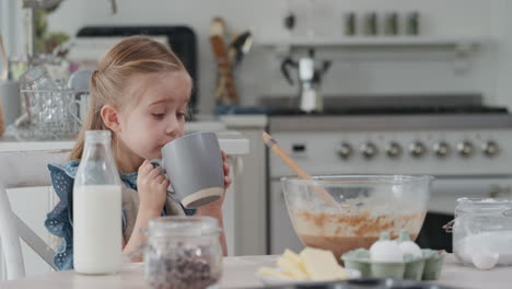 Lustiges-Kleines-Mädchen,-Das-In-Der-Küche-Heiße-Schokolade-Trinkt-Und-Zu-Hause-Köstliche-Leckereien-Genießt,-Nachdem-Es-In-Der-Küche-4k-Gebacken-Hat