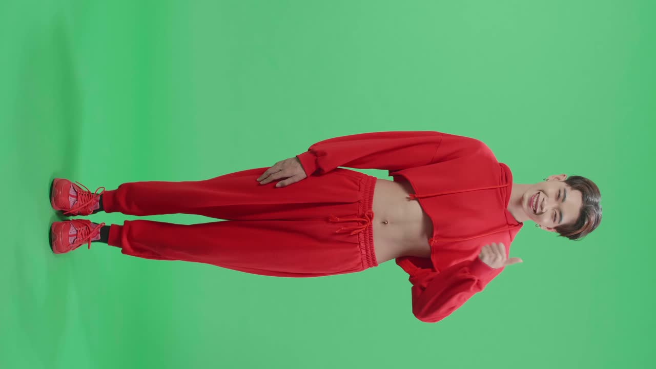 Full Body Of Happy Asian Transgender Male Showing Thumbs Up Gesture While Standing In The Green Screen Studio