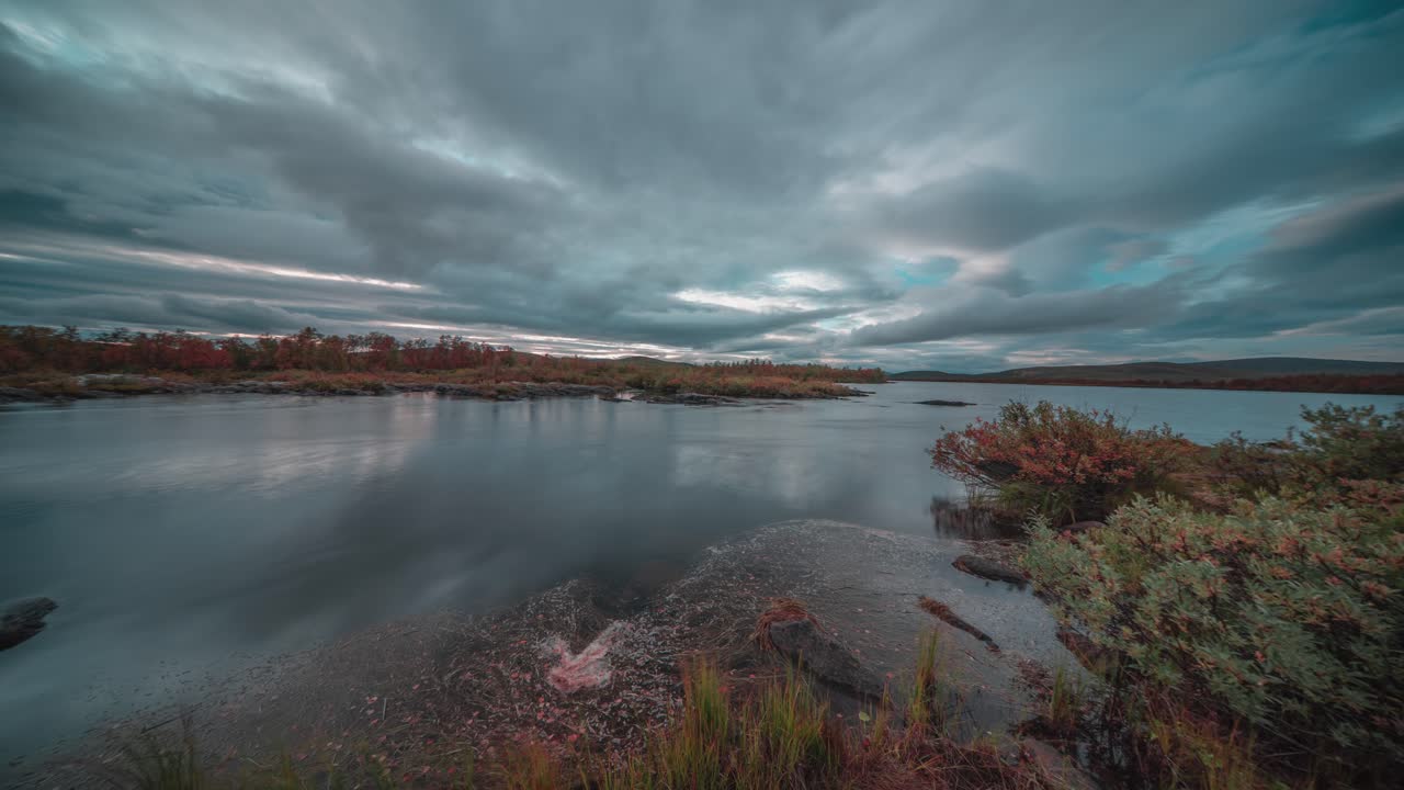 un río sereno refleja las nubes iluminadas por el sol mientras la hermosa puesta de sol domina el cielo