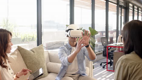 vr headset, man exploring virtual interior design while multiracial colleagues watch, at office