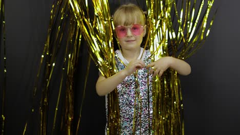 Happy-child-dancing,-playing,-fooling-around-in-shiny-foil-fringe-golden-curtain.-Little-blonde-kid