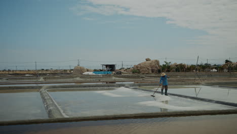 a person working in a salt farm under a sunny sky
